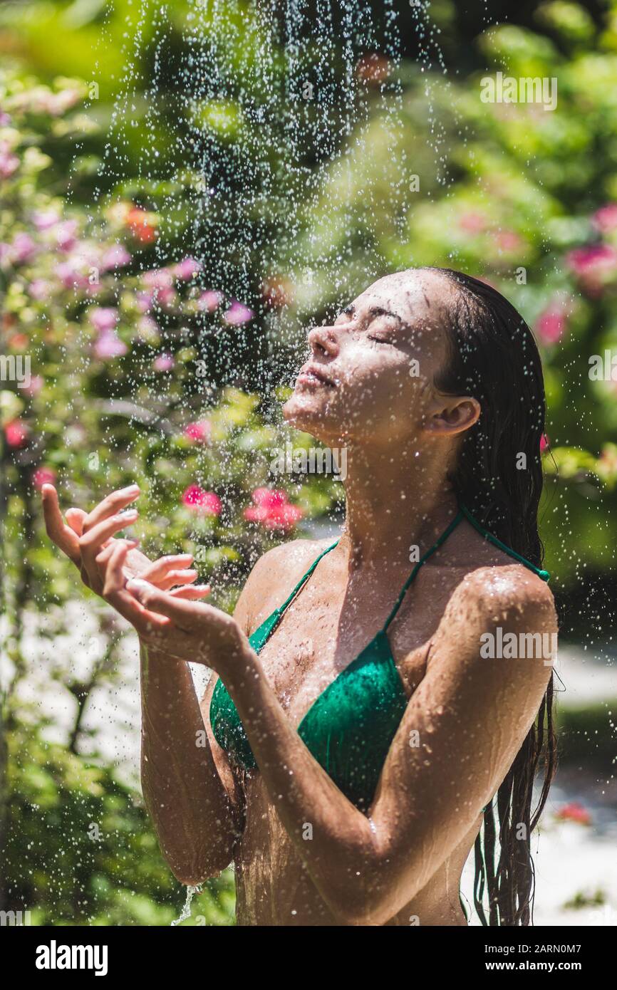 Mujer tomar una ducha exterior en el jardín verde tropical de Bali con un  montón de flores. Fresh salpicaduras de agua limpia. Spa de lujo Fotografía  de stock - Alamy