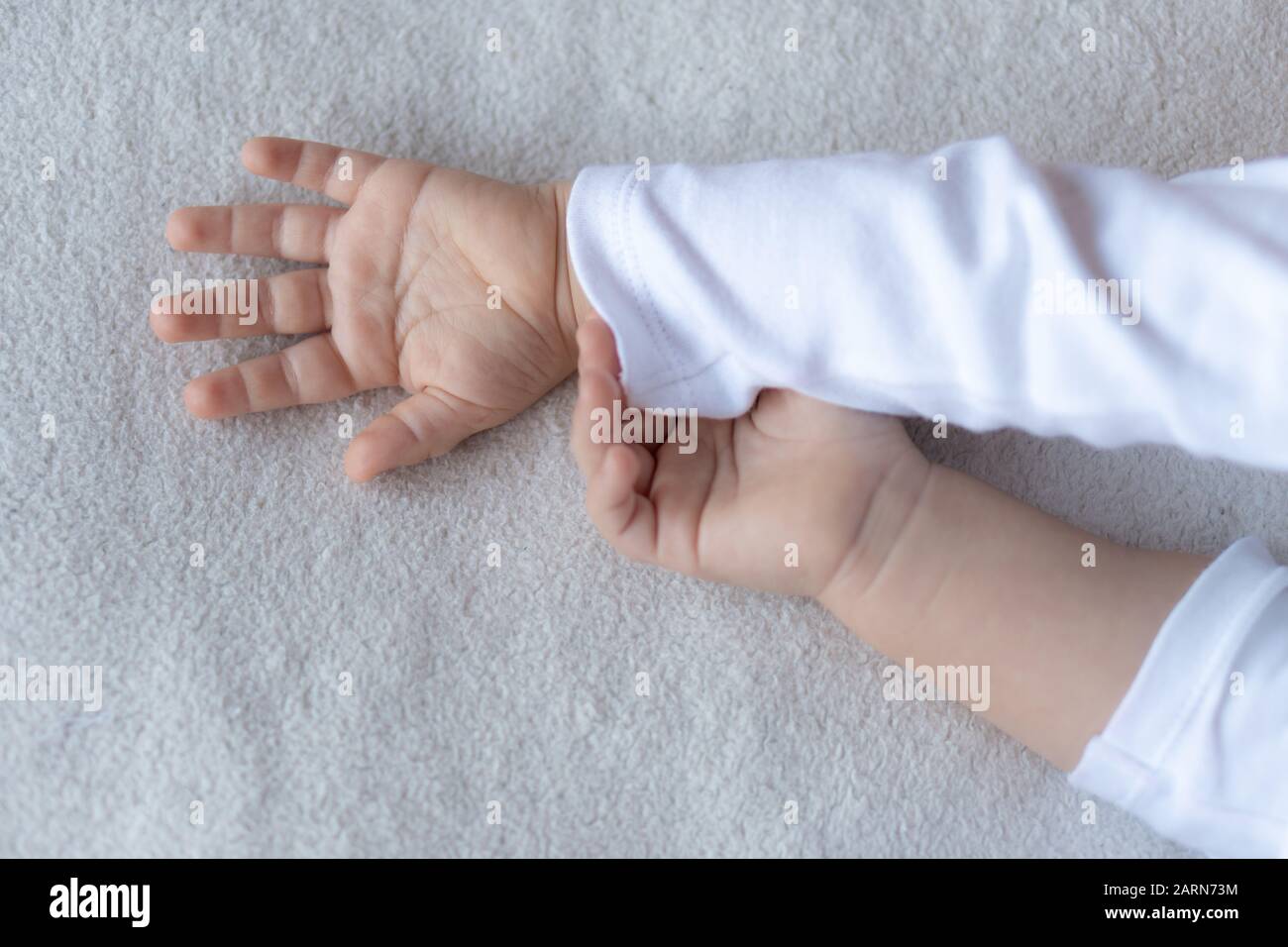 Hand of the child in a hand of mother on a pillow. Stock Photo
