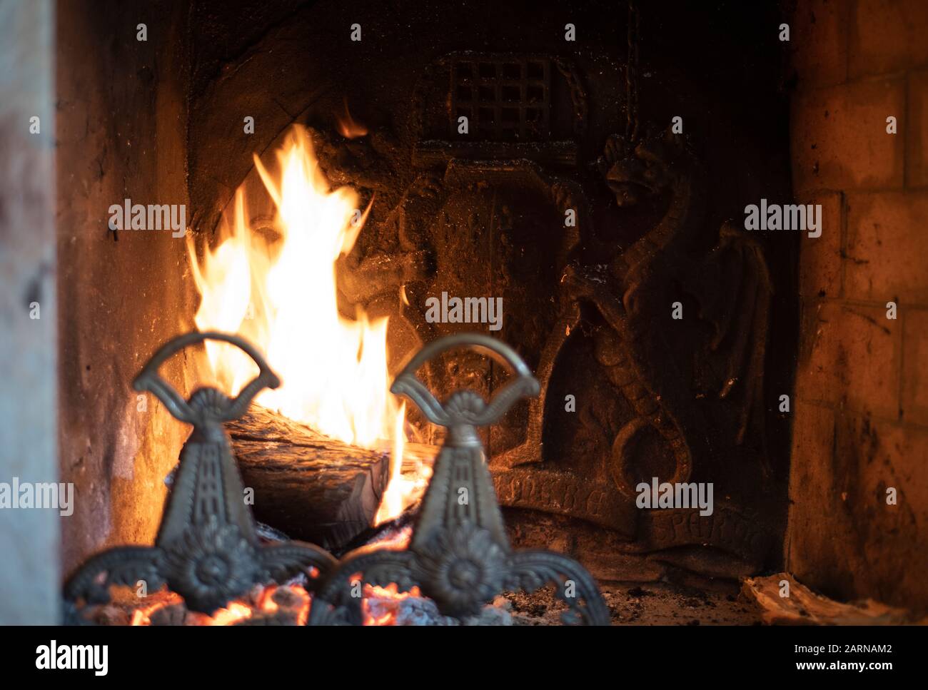 Fire burning in a dragon fireplace in an old house with the mystical beasts  depicted on the metal back plate and andirons in the foreground Stock Photo  - Alamy