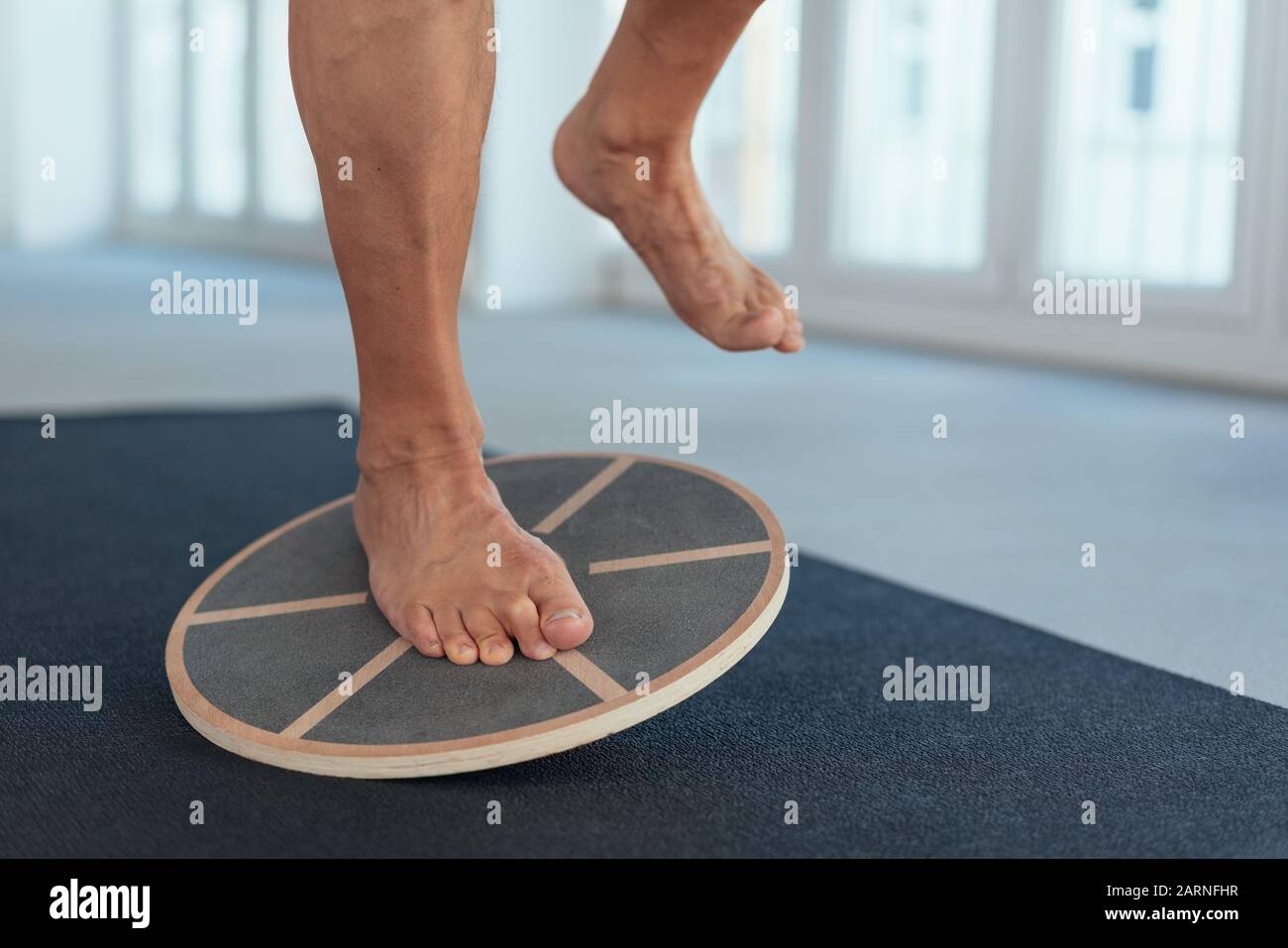 Man strengthening his leg muscles working out using a balance board in