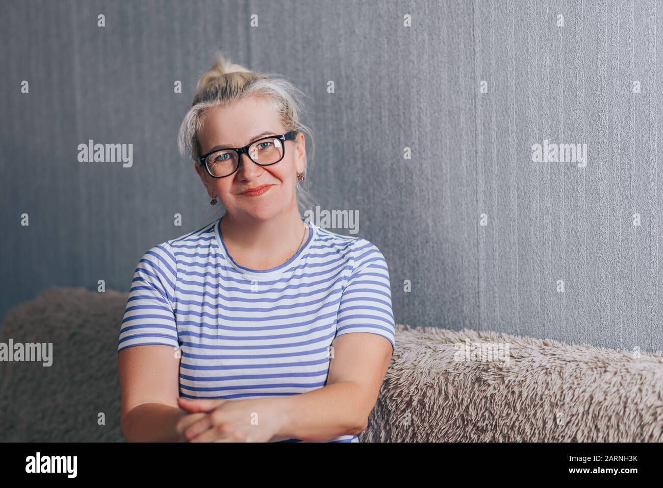 Smiling mature woman sitting on sofa Stock Photo - Alamy