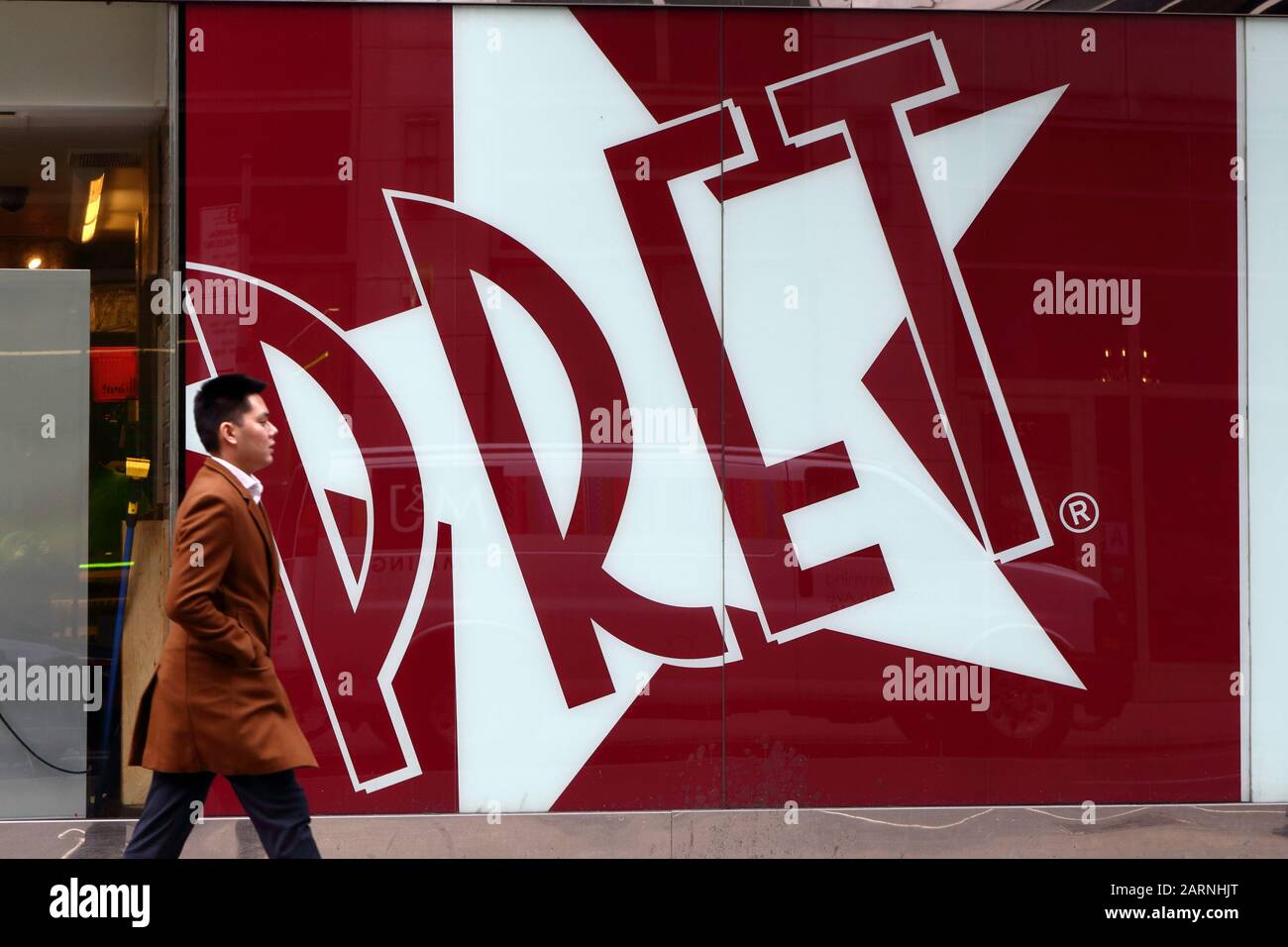 A person walks by a giant Pret A Manger logo at a shop in New York, NY. Stock Photo