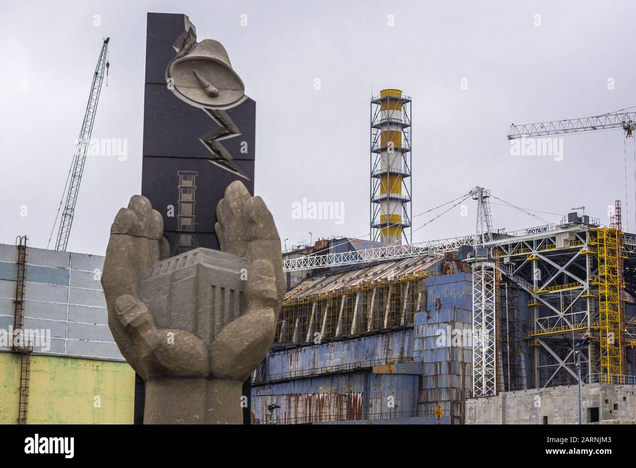 Monument to the Chernobyl Victims and Reactor number 4 old sarcophagus of Chernobyl Nuclear Power Plant in Zone of Alienation, Ukraine Stock Photo