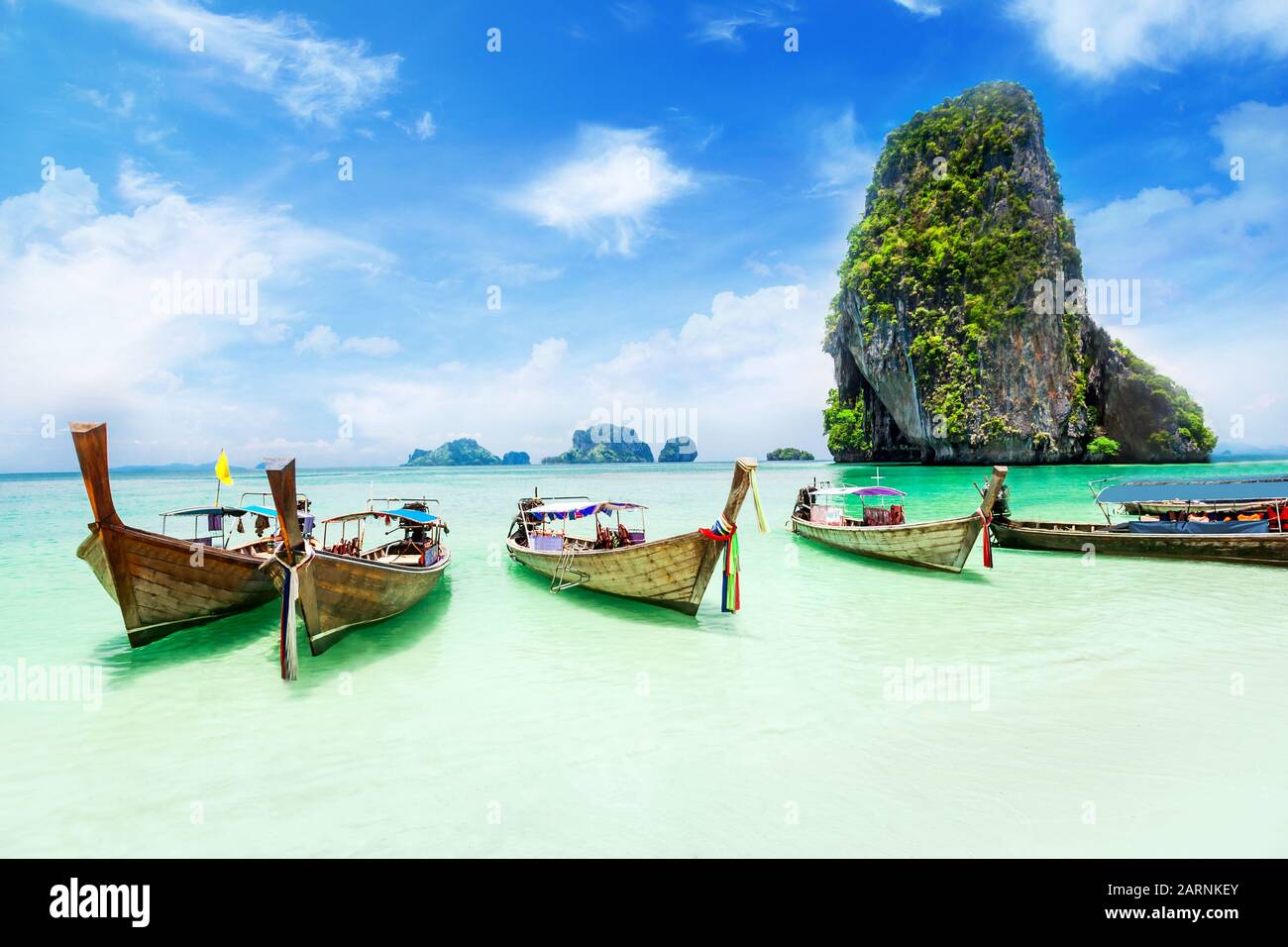 Longtale boats at the Phuket beach with limestone rock on background in Thailand. Stock Photo