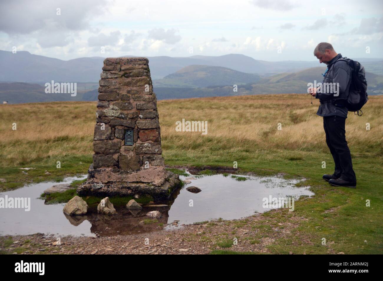 Man Checking GPS Compass by the Summit Cairn of the Wainwright 'Loadpot Hill' in the Lake District National Park, Cumbria, England, UK Stock Photo