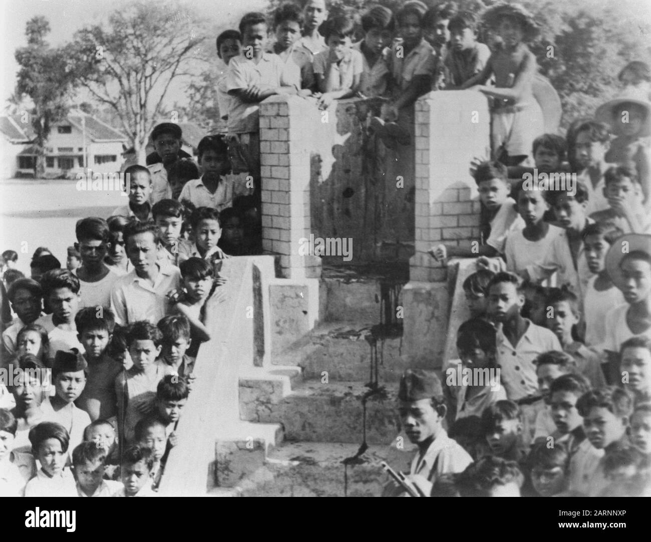 Photographs killed communists by the TNI [made in Madioen, September 1948]  Audience, including many children, in public execution. Around a building with a staircase. Blood drips the steps Date: September 1948 Location: Indonesia, Dutch East Indies Stock Photo