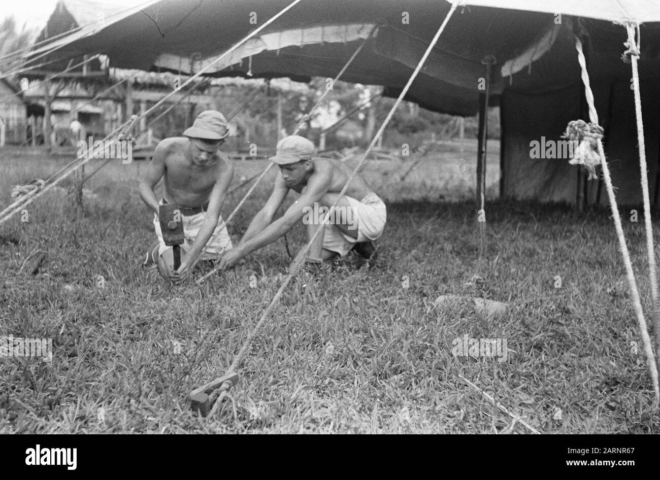 Recordings concerning border traffic  [Tinggi Hari. Two soldiers store pegs for building tents] Date: 29 July 1948 Location: Indonesia, Java, Dutch East Indies, Tinggi Hari Stock Photo
