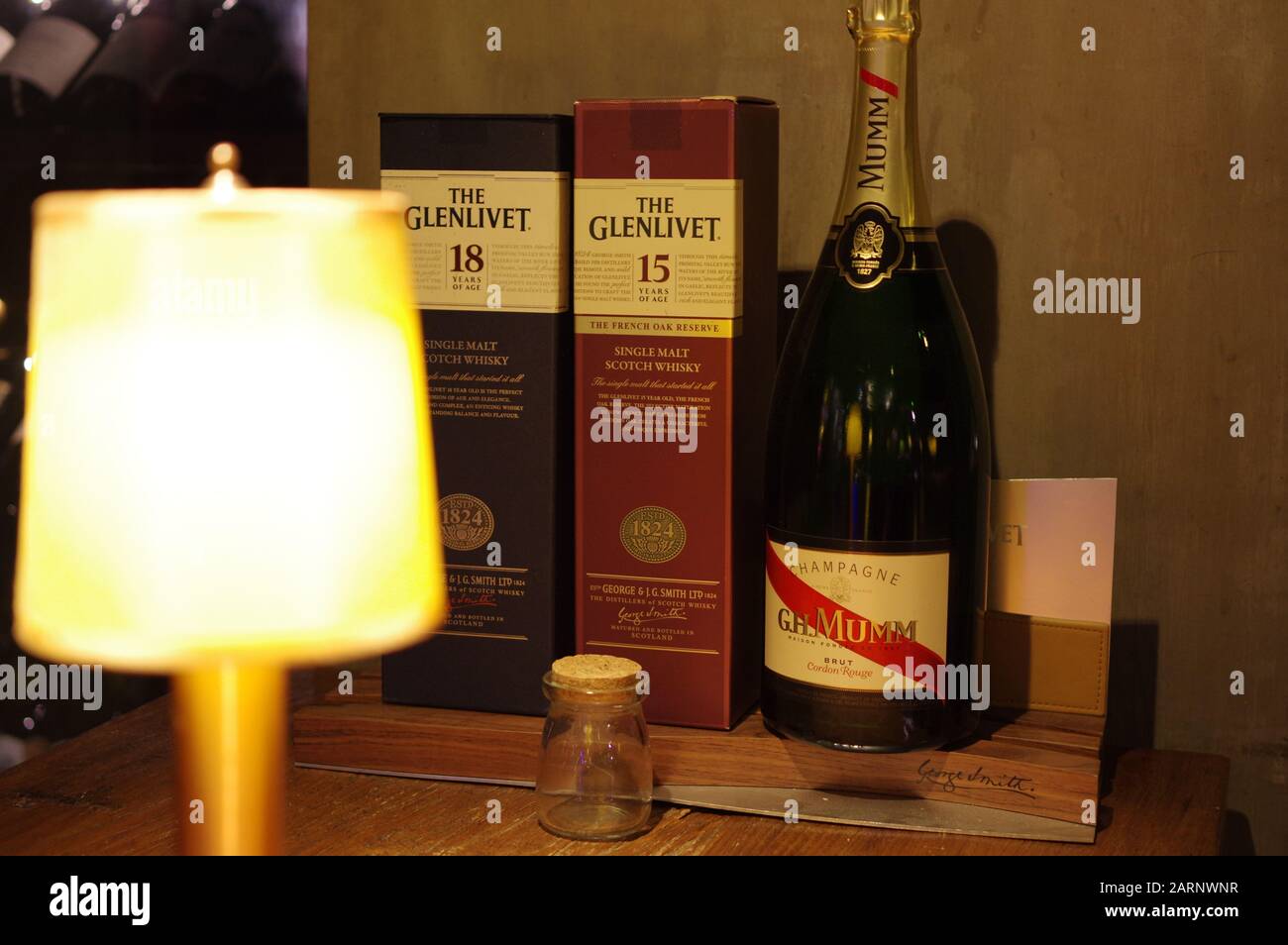 G. H. Mumm champagne and The Glenlivet single-malt scotch whisky packages displayed on wooden table Stock Photo