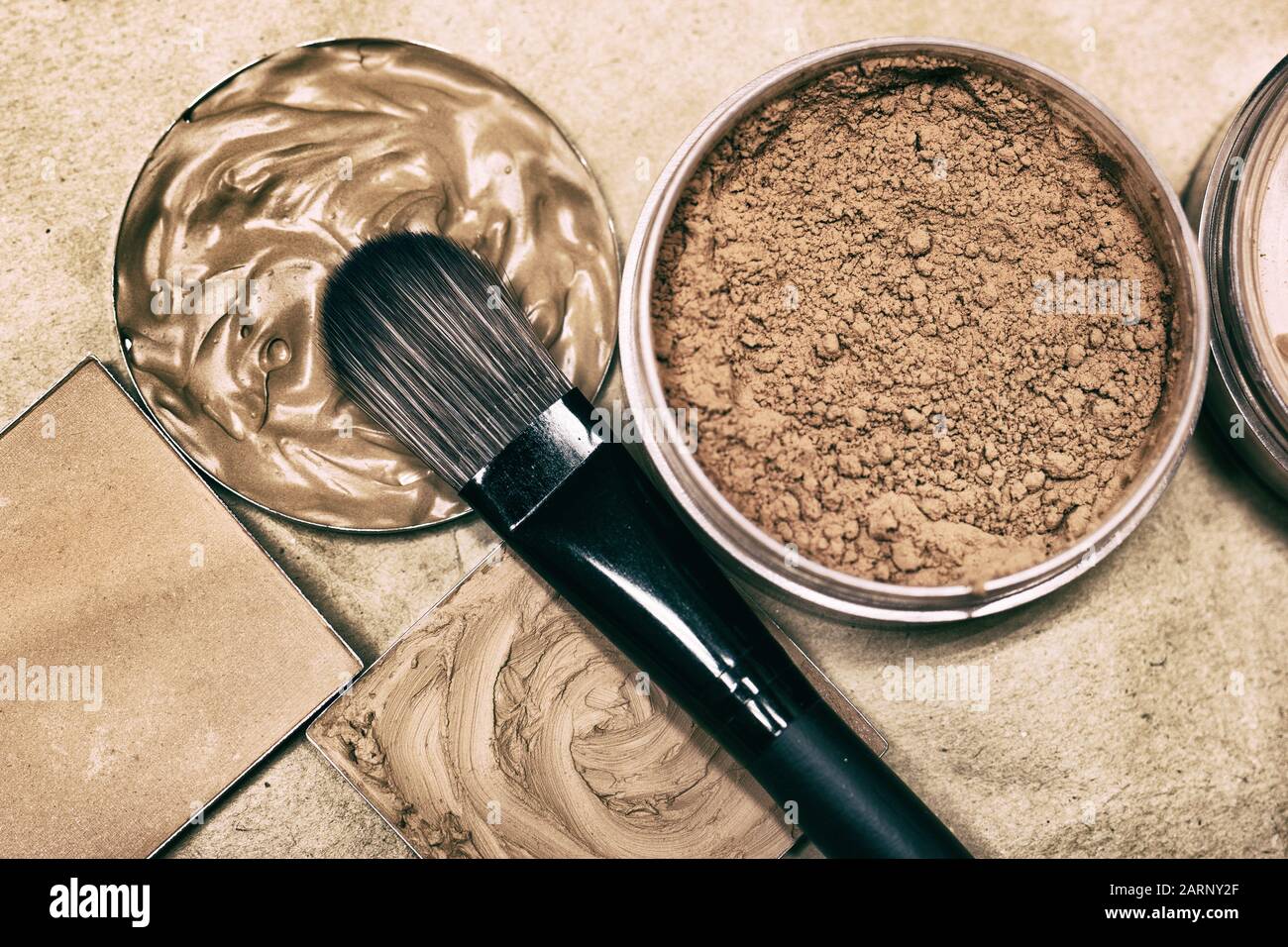 Make-up brush with concealer, makeup foundation and powder - closeup, top view. Retro style processing Stock Photo
