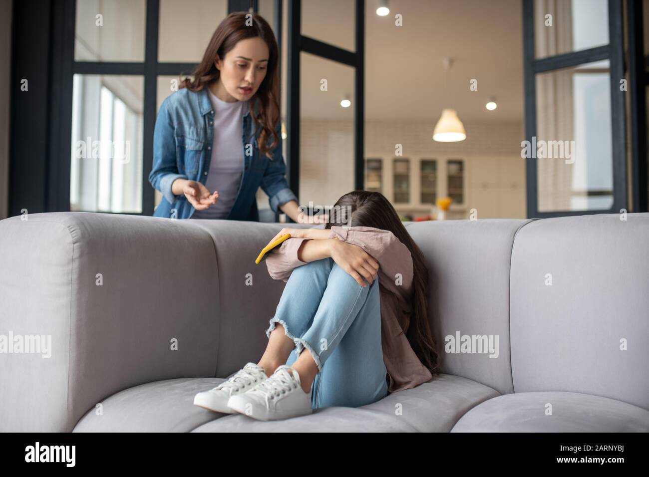 Crying daughter hiding her face and mom standing next to her Stock Photo -  Alamy