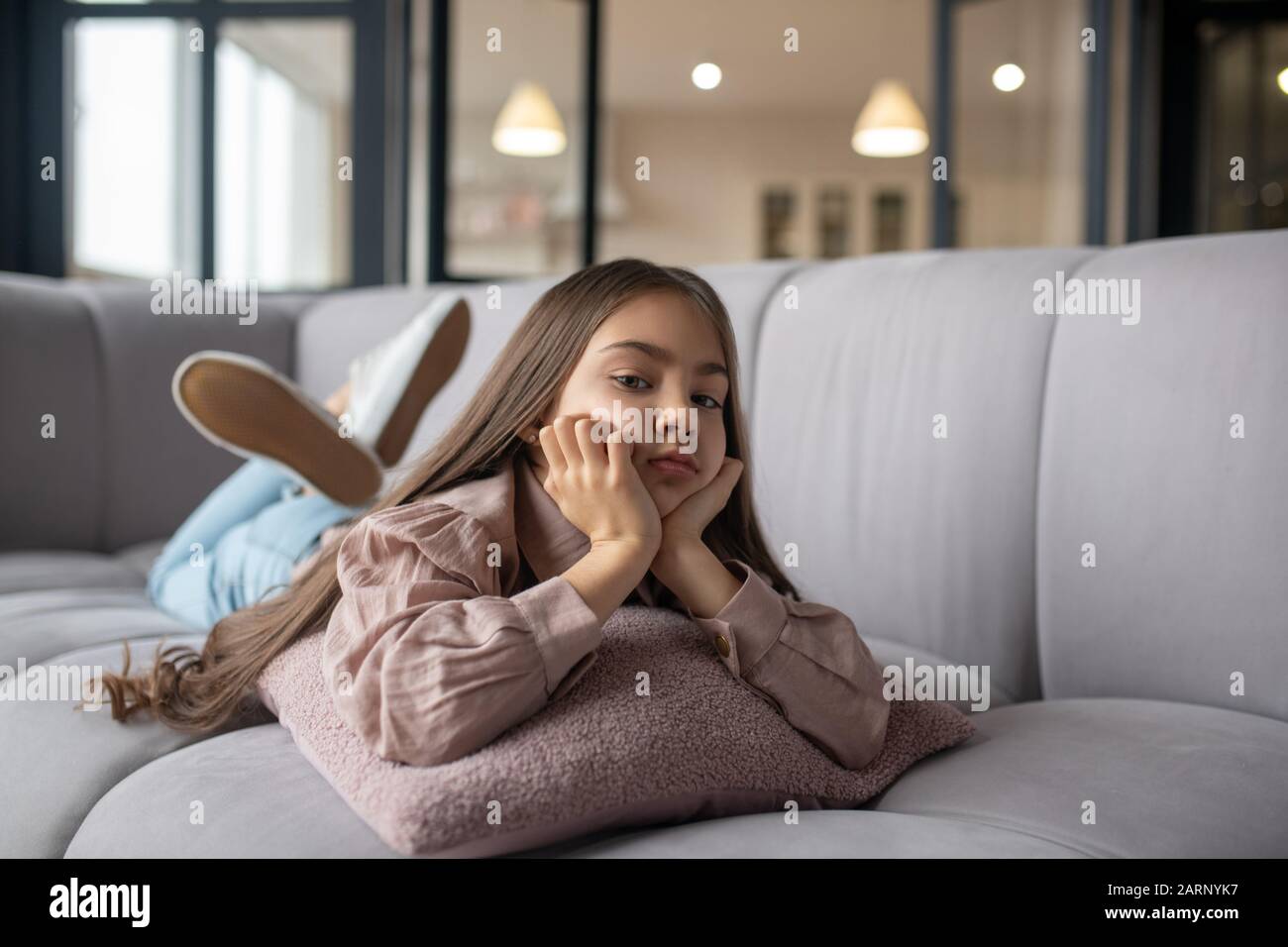 Sad little girl lying on a sofa at home Stock Photo - Alamy