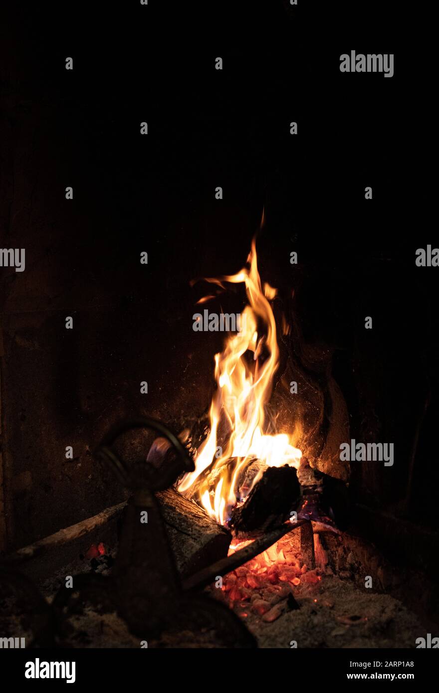 Fiery flames of a burning fire in a brick fireplace glowing in the darkness for heating in winter Stock Photo