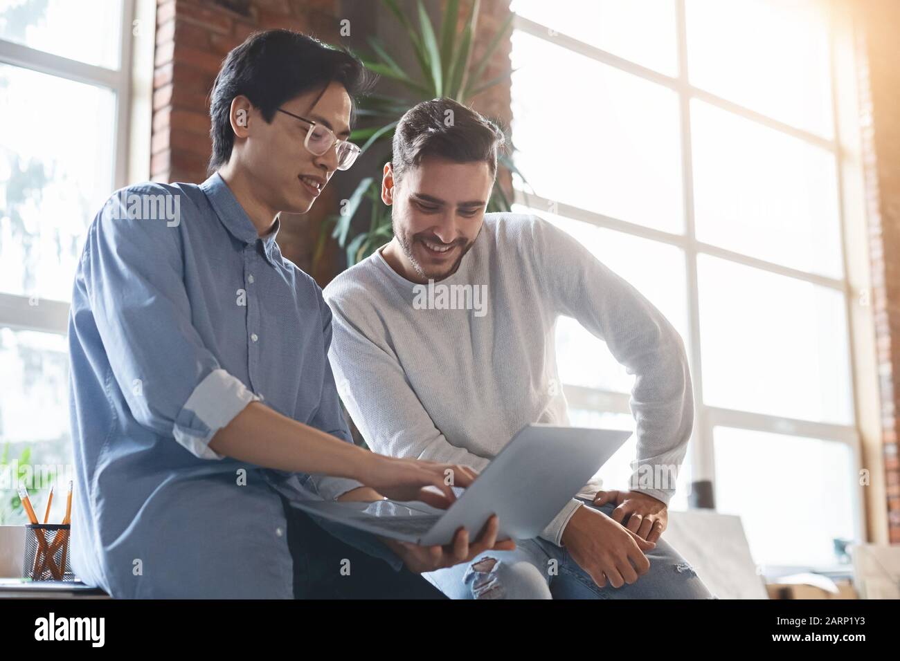 Two men colleagues sharing creative ideas, using digital tablet Stock Photo
