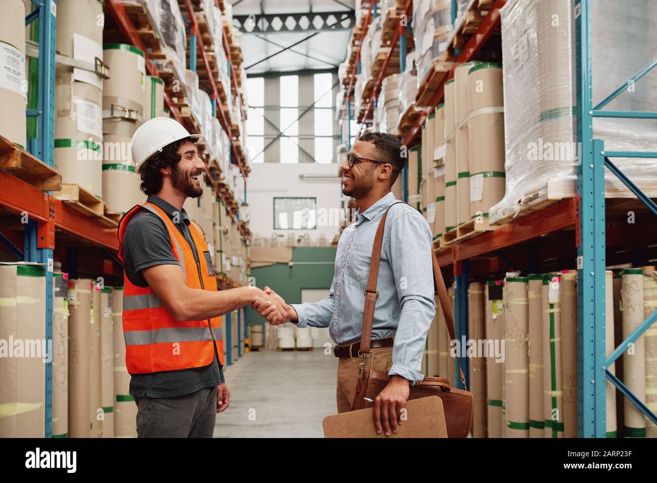 Banker and business owner shaking hands in a modern factory - two men making a deal  Stock Photo