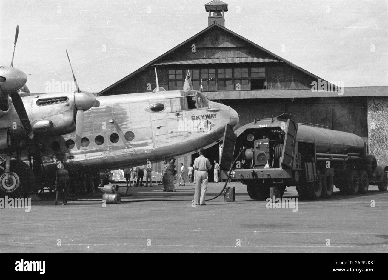 [a four-engine aircraft of Skyway has landed and is on the platform of an airport. Flags are stuck out of the cockpit. A tank car refuel] Date: June 1947 Location: Indonesia, Dutch East Indies Stock Photo