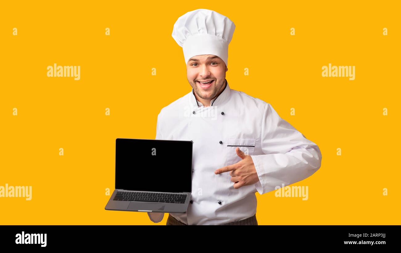 Chef Showing Laptop With Empty Screen Standing, Yellow Background, Panorama Stock Photo