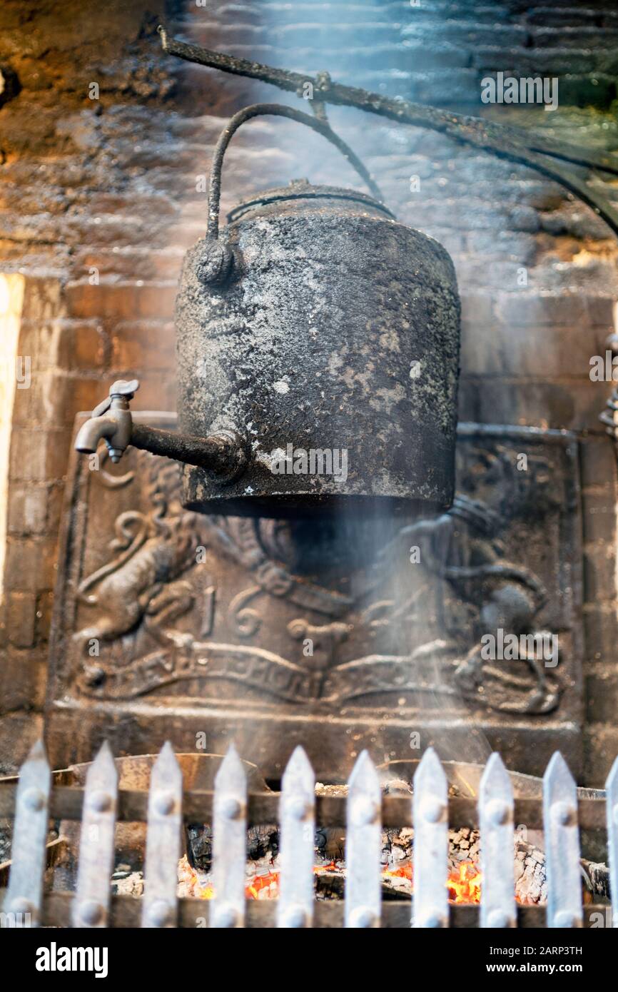 Vintage kettle in the smoke of fireplace in old English pub, UK Stock