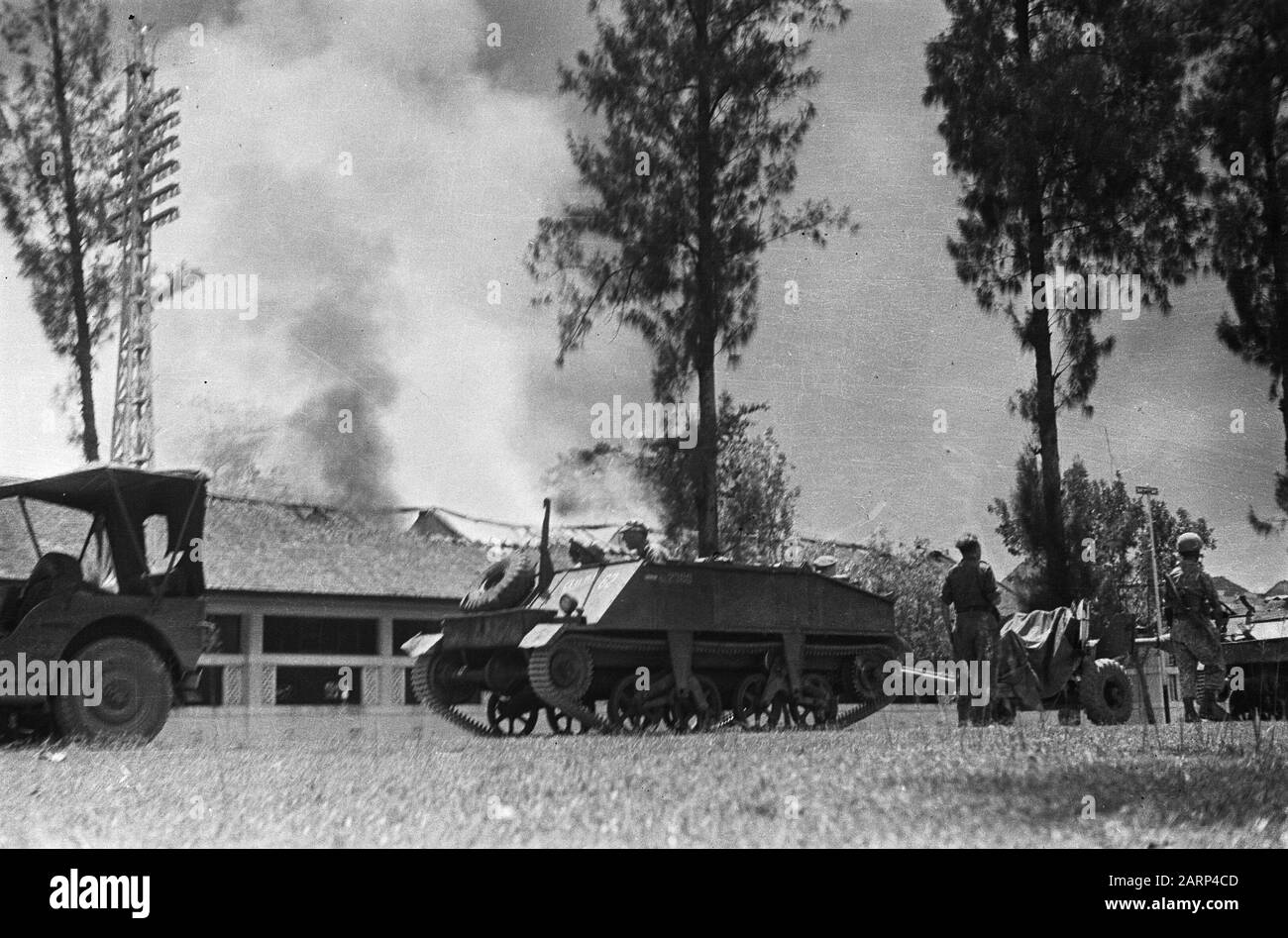 The advance of the V-Brigade  Jeep and artillery pullers stand still. Behind it a burning building Date: 20 December 1948 Location: Indonesia, Dutch East Indies Stock Photo