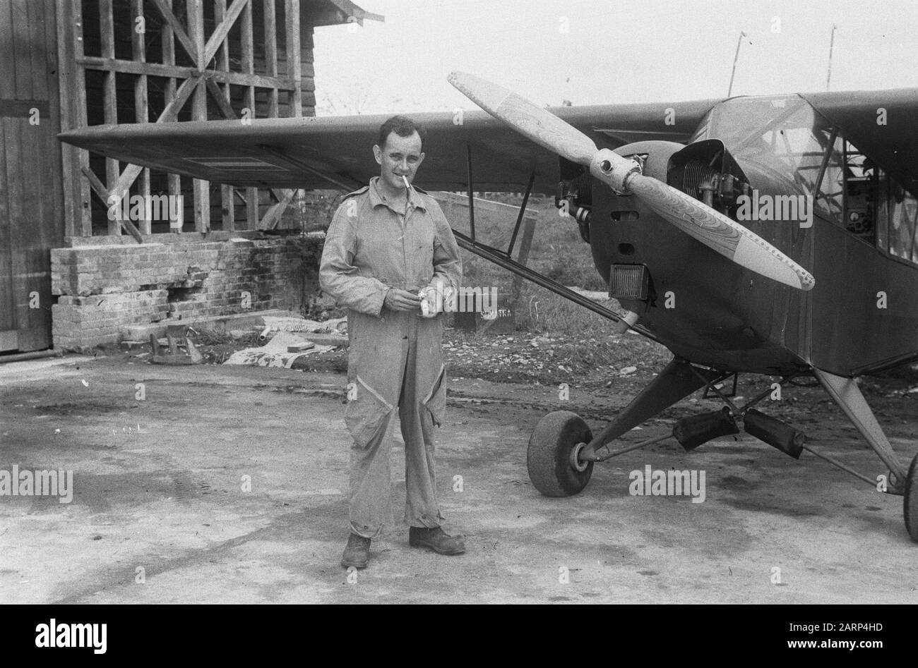 Flyman poses bji Piper L-4J Cub Grashopper Annotation: On the block or box behind the plane stands Sumatra. Registration number: PC4-006. This aircraft was later renumbered R-306 and was transferred to the Indonesian Air Force (AURIS) in 1950. Date: 1946 Location: Indonesia, Dutch East Indies Stock Photo