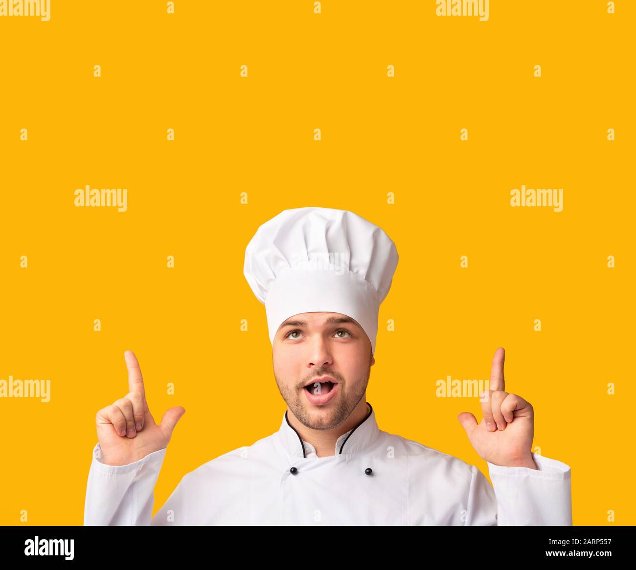 Cook Man Pointing Fingers Up Over Yellow Background, Studio Shot Stock Photo