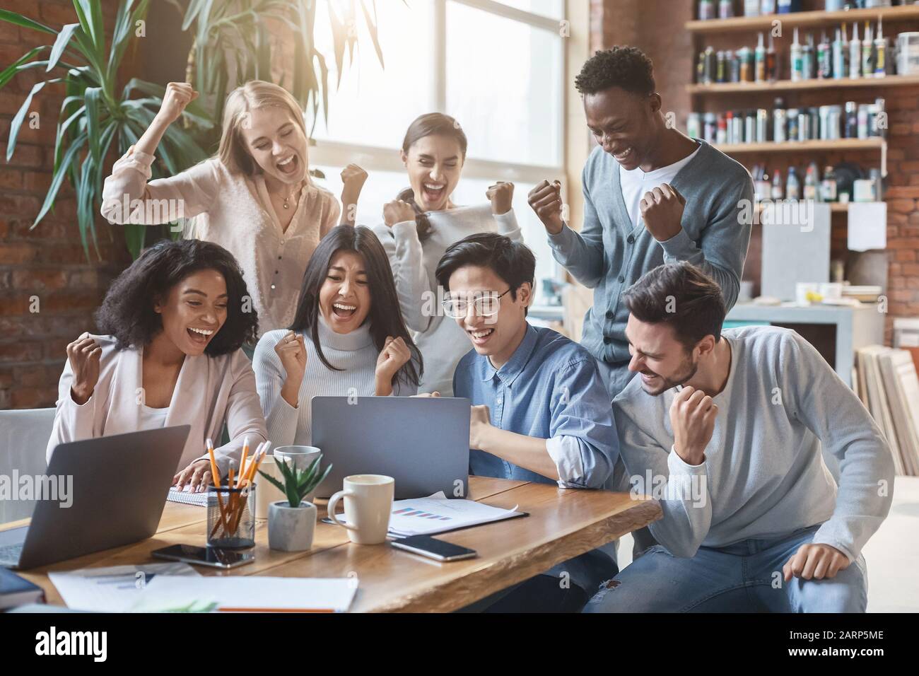 International business team looking at laptop screen, celebrating ...