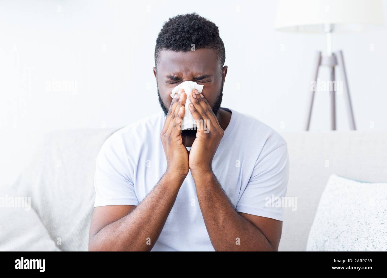 Sick african guy cleaning his snotty nose at home Stock Photo