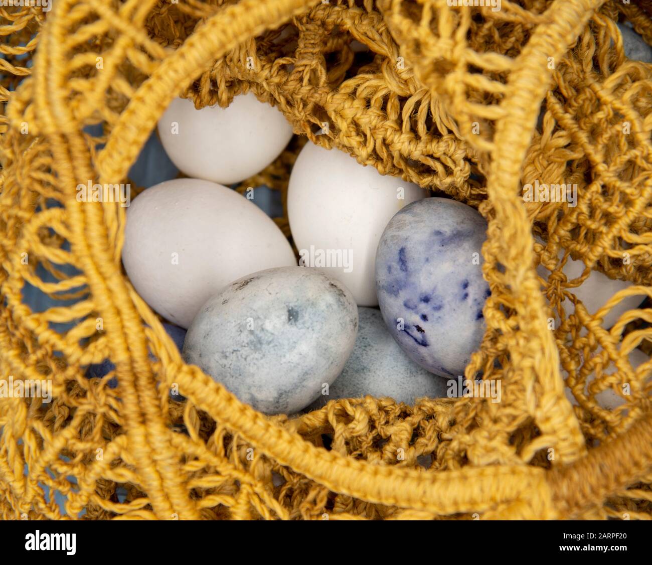 White and painted eggs in a wicker string bag . Stock Photo