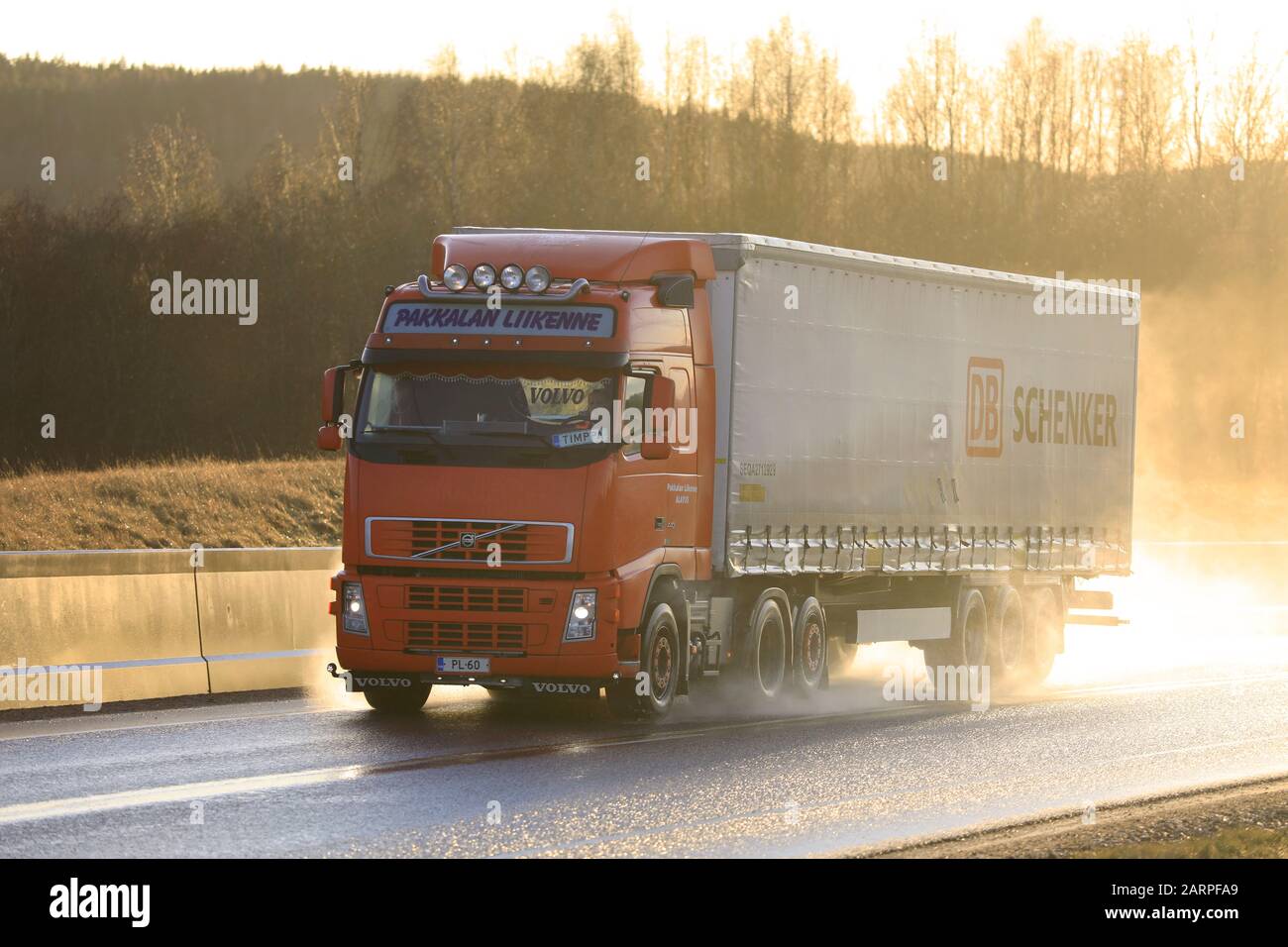 Red Volvo FH 440 Pakkalan Liikenne Oy pulls DB Schenker cargo trailer along wet highway in the golden light of sunset. Salo, Finland. January 24, 2020 Stock Photo