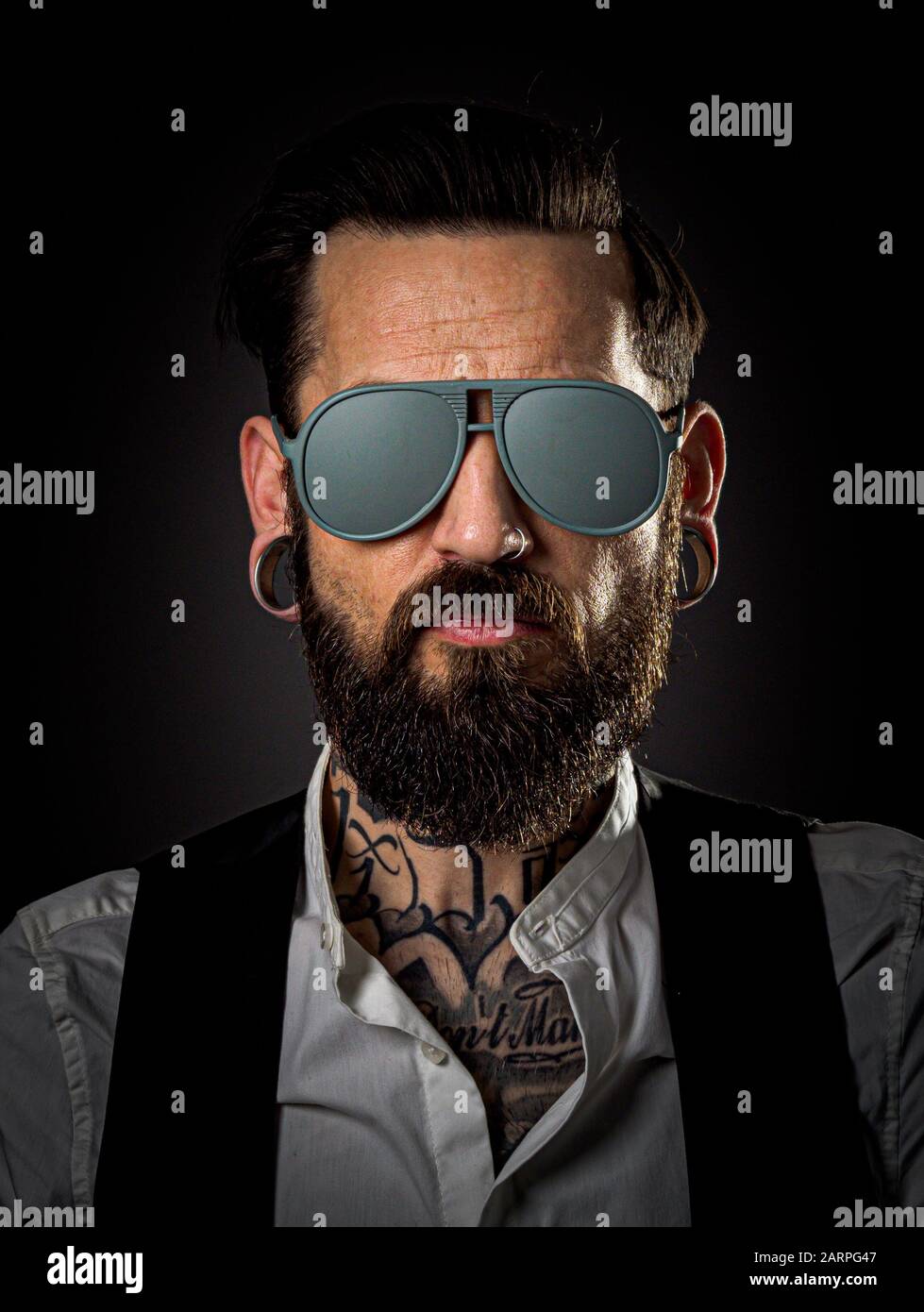 Studio Portrait of a male model with beard and tattoos. Wearing grey sunglasses Stock Photo