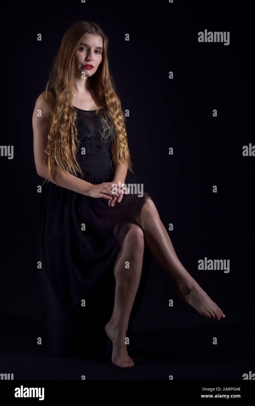 Attractive woman posing in a black dress in a studio setting Stock Photo