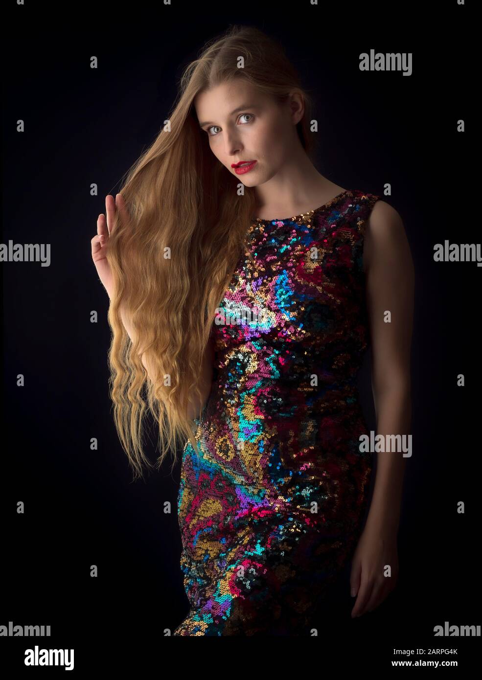 Young woman posing in stylish sequin dress in a studio setting Stock Photo