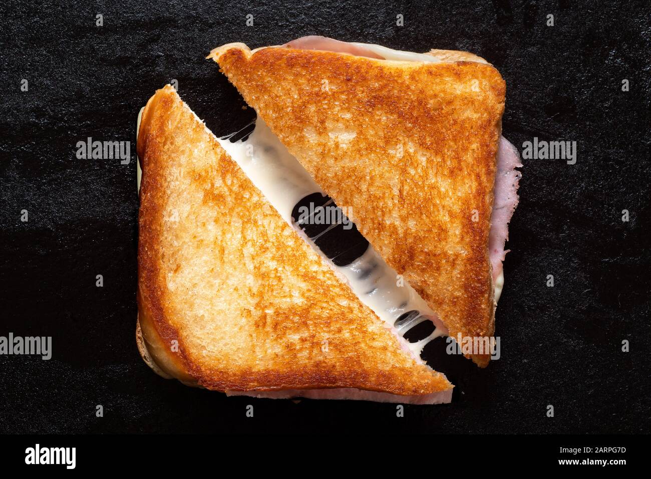 Classic cheese and ham toasted sandwich cut in half isolated on black