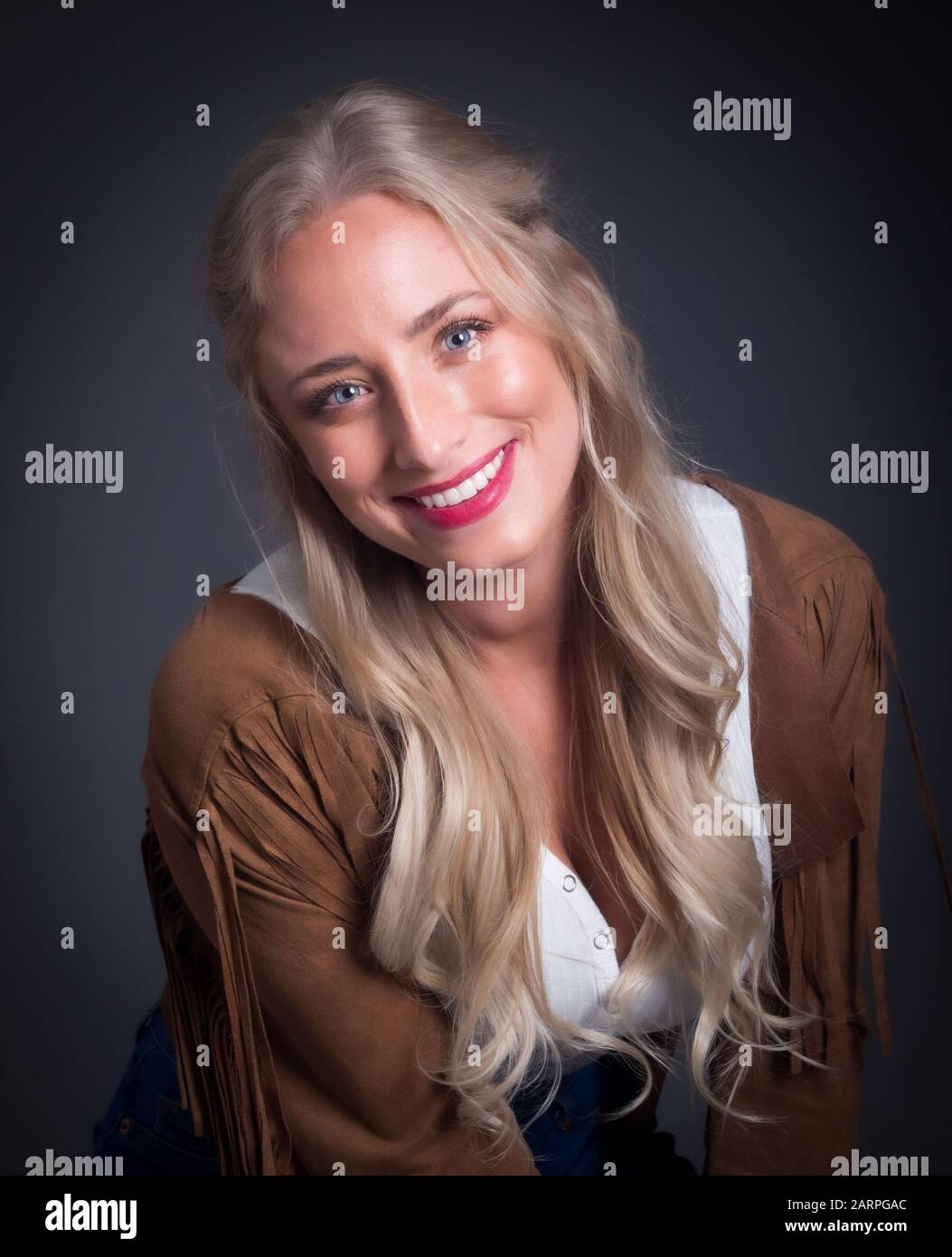 Attractive woman posing in a cowboy style fringe outfit in studio setting Stock Photo