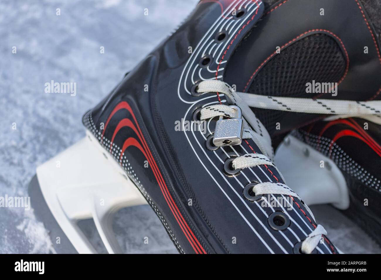 Hockey skates on ice and a closed lock with laces closeup, as a symbol