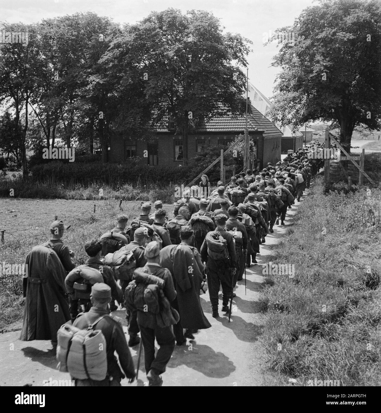 Capitulation: Den Helder [embarkation of Germans]  [German prisoners of war in column passing a farm] Date: 1945 Location: Den Helder Keywords: prisoners of war, Second World War Stock Photo