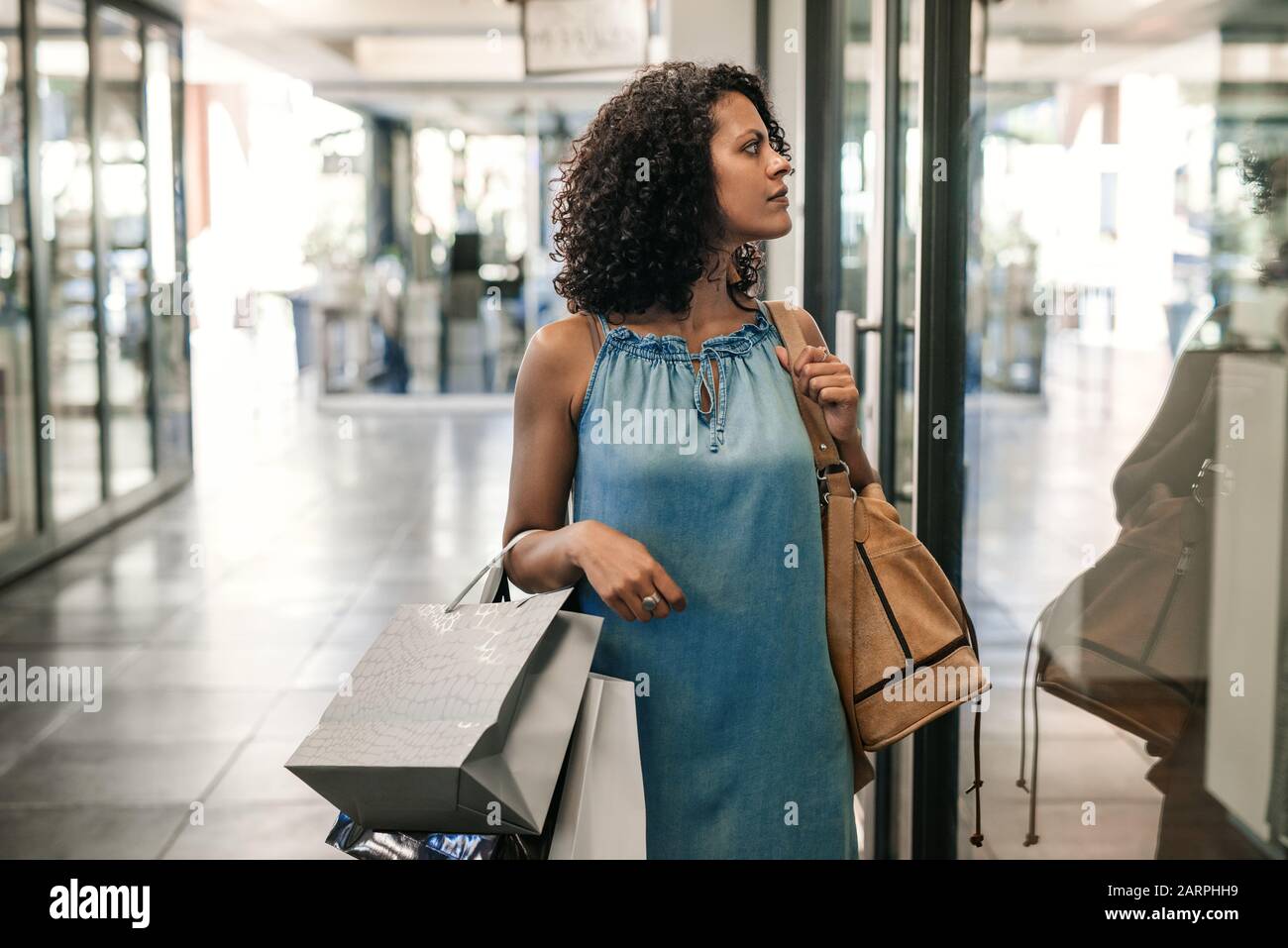 Young woman carrying bags and window shopping in a mall Stock Photo