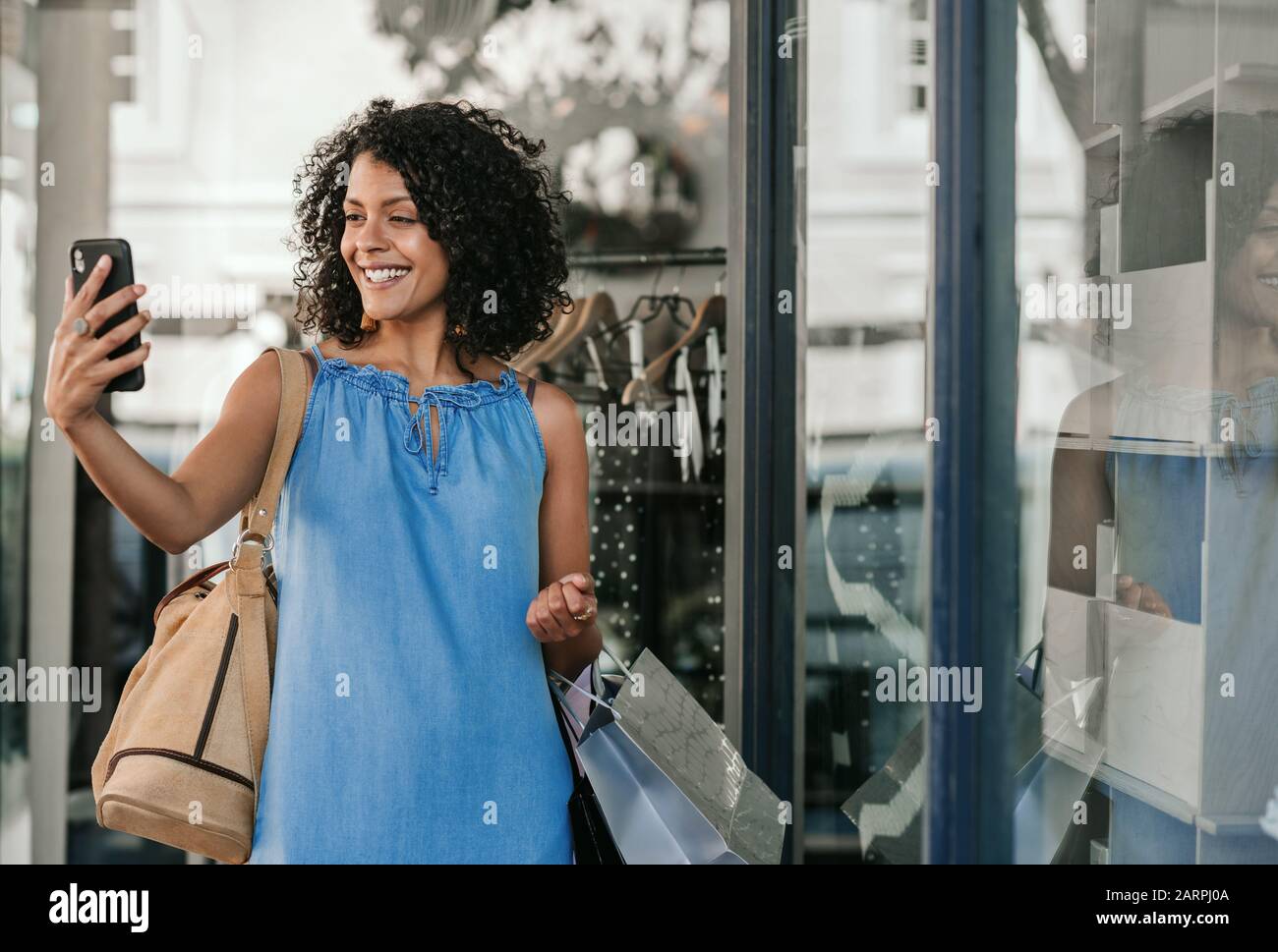 Smiling woman taking selfies while out clothes shopping Stock Photo