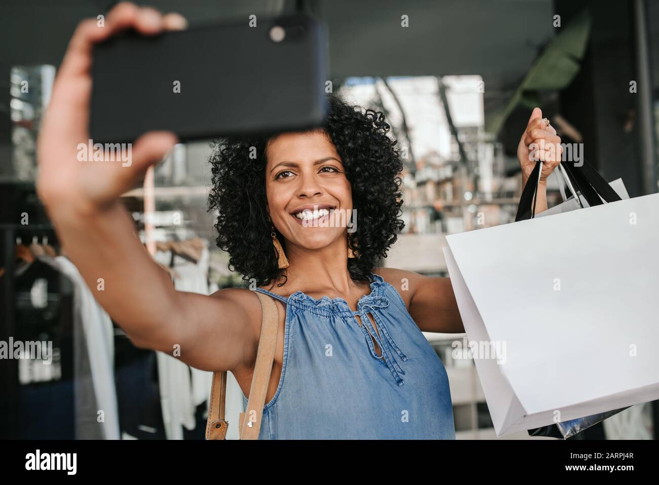 Smiling young woman taking selfies while out shopping Stock Photo