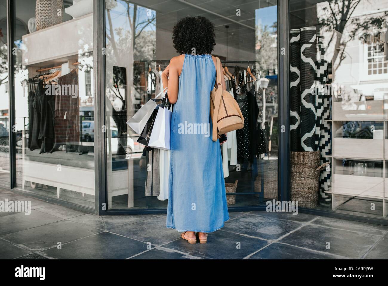 Woman looking at a storefront display while out clothes shopping Stock Photo