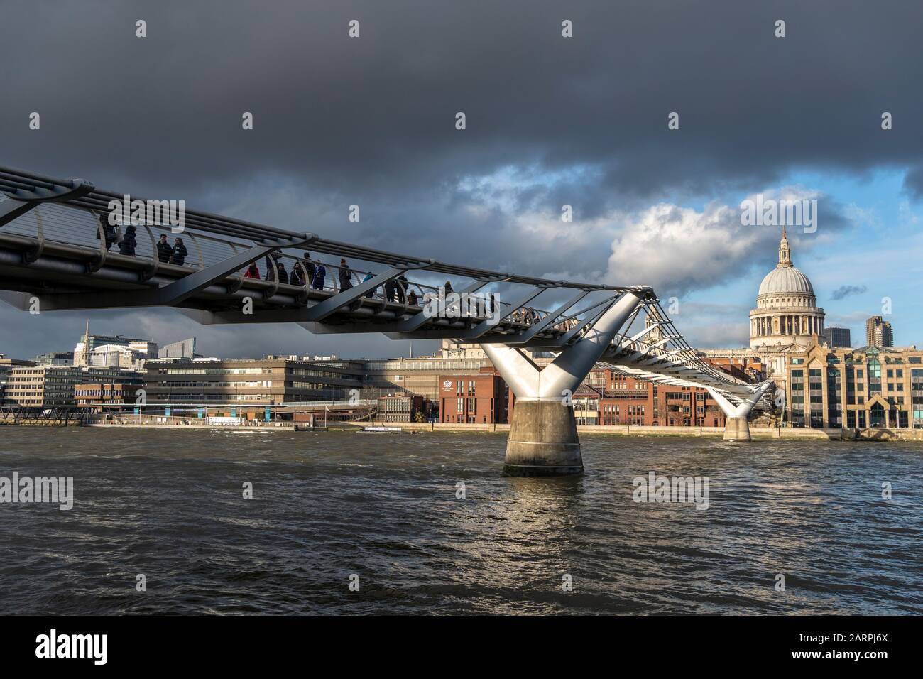 LONDON - JANUARY 28: Pedestrians cross London’s Millennium Bridge in winter sunlight, that shines on the dome of St. Paul’s Cathedral, as two swans pass on the River Thames. Photo: © 2020 David Levenson Stock Photo