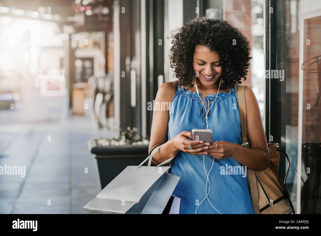 Smiling woman listening to music while out shopping for clothing Stock Photo