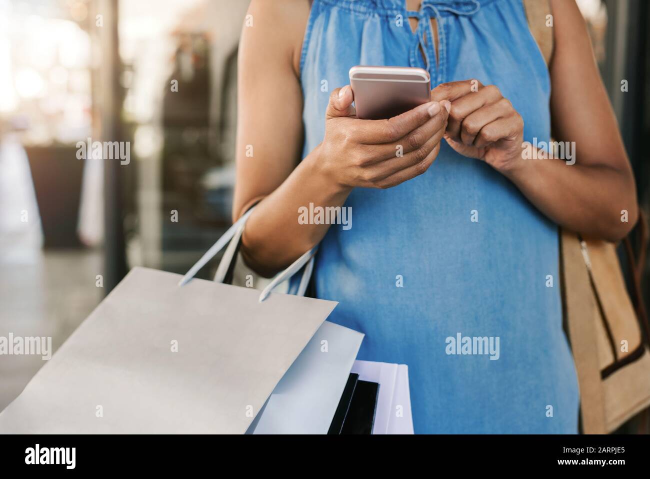 Woman using her cellphone while out clothes shopping Stock Photo