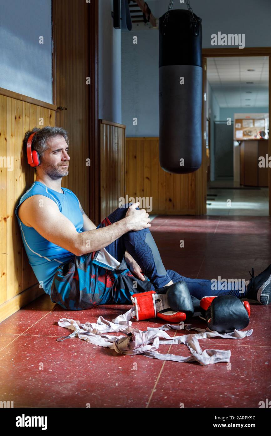 Young boxer listening to music with headphones while resting in the gym Stock Photo