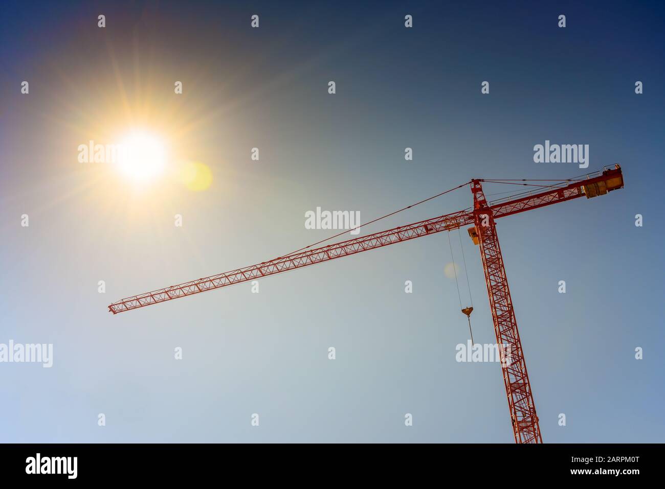 Industrial crane and sun on blue sky background Stock Photo