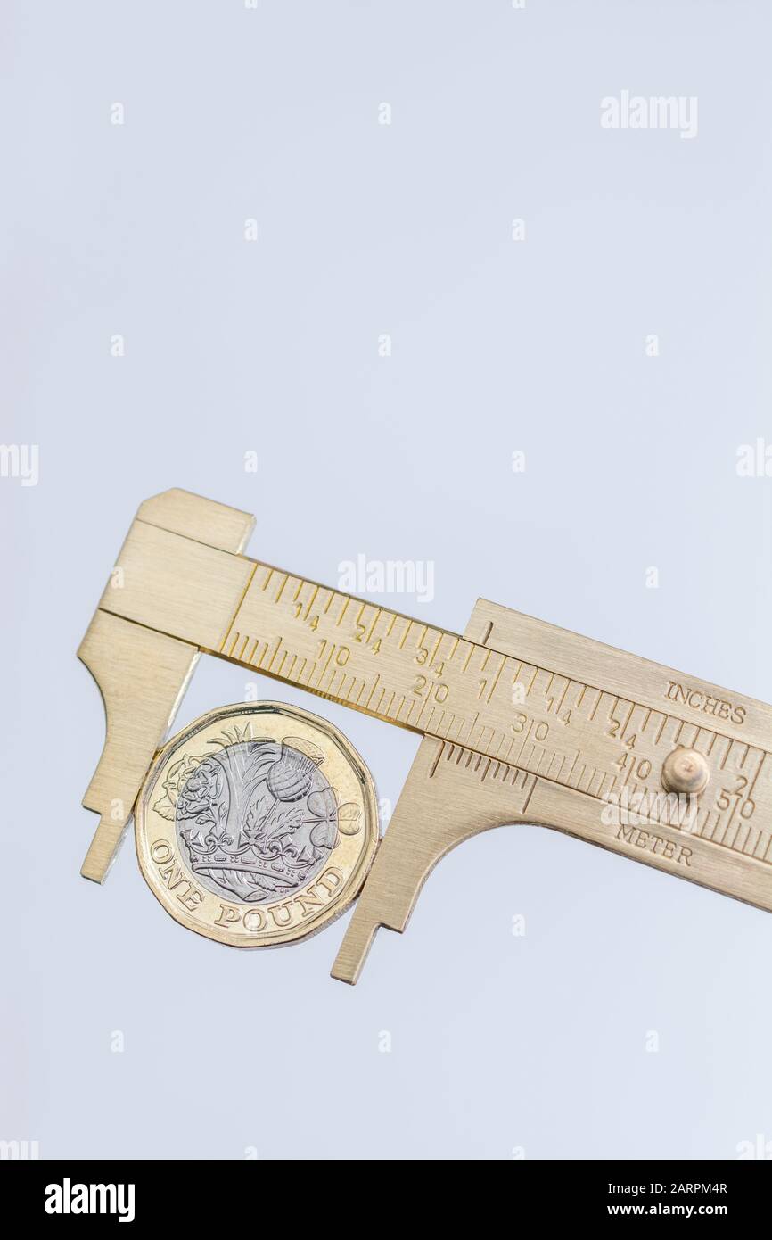 UK new pound coin between brass Vernier caliper jaws. For price