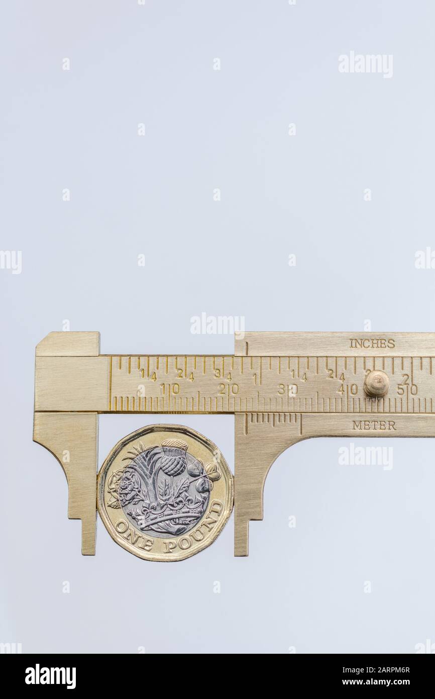 UK new pound coin between brass Vernier caliper jaws. For price