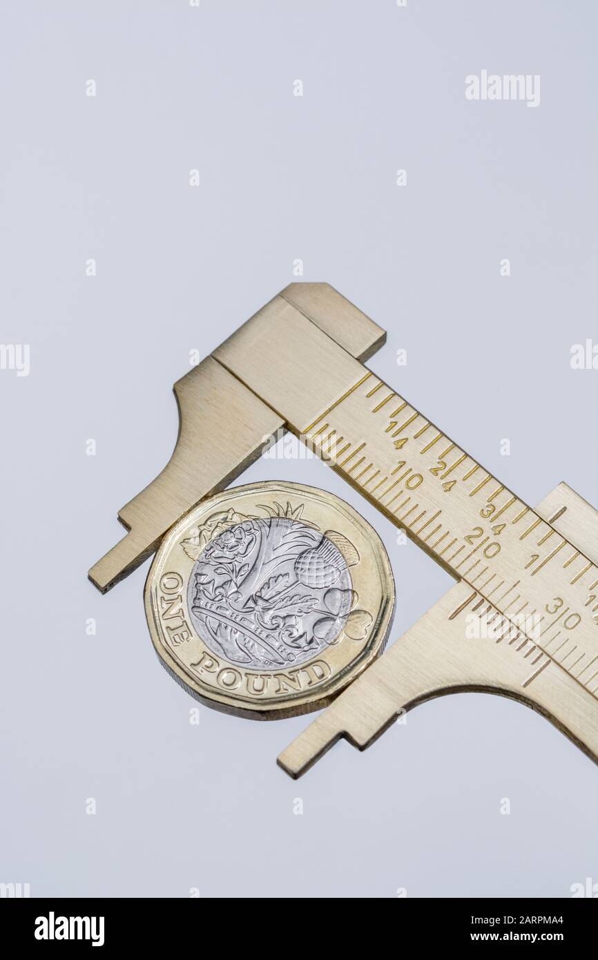 UK new pound coin between brass Vernier caliper jaws. For price