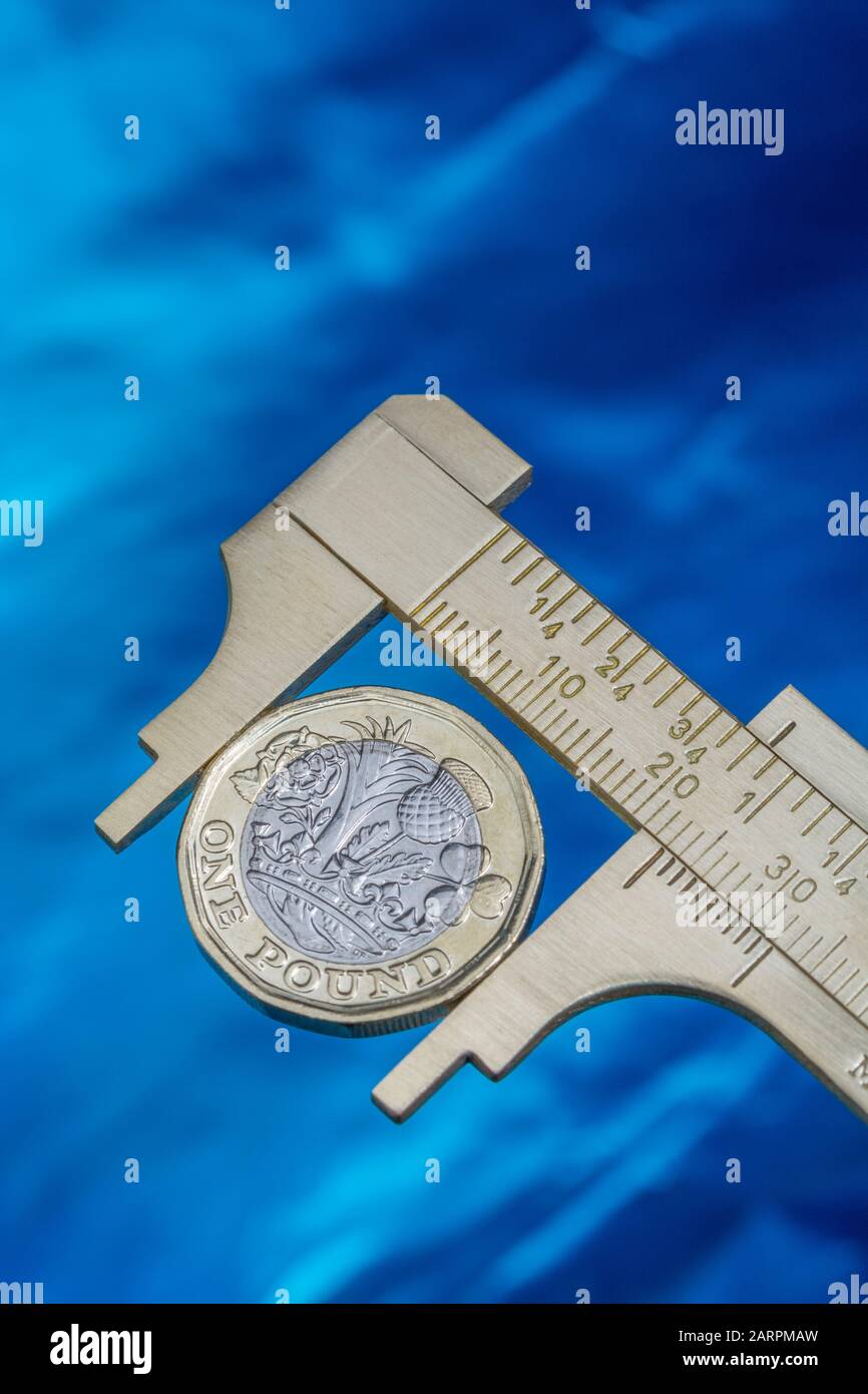 UK new pound coin between brass Vernier caliper jaws. For price