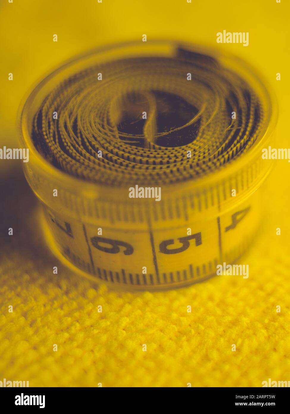 Yellow measuring tape in round plastic box on the towel. Stock Photo