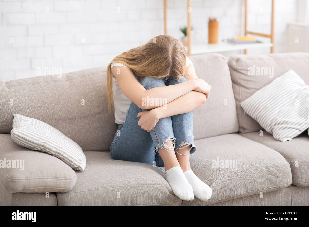 Hopeless girl sitting on couch and crying Stock Photo - Alamy
